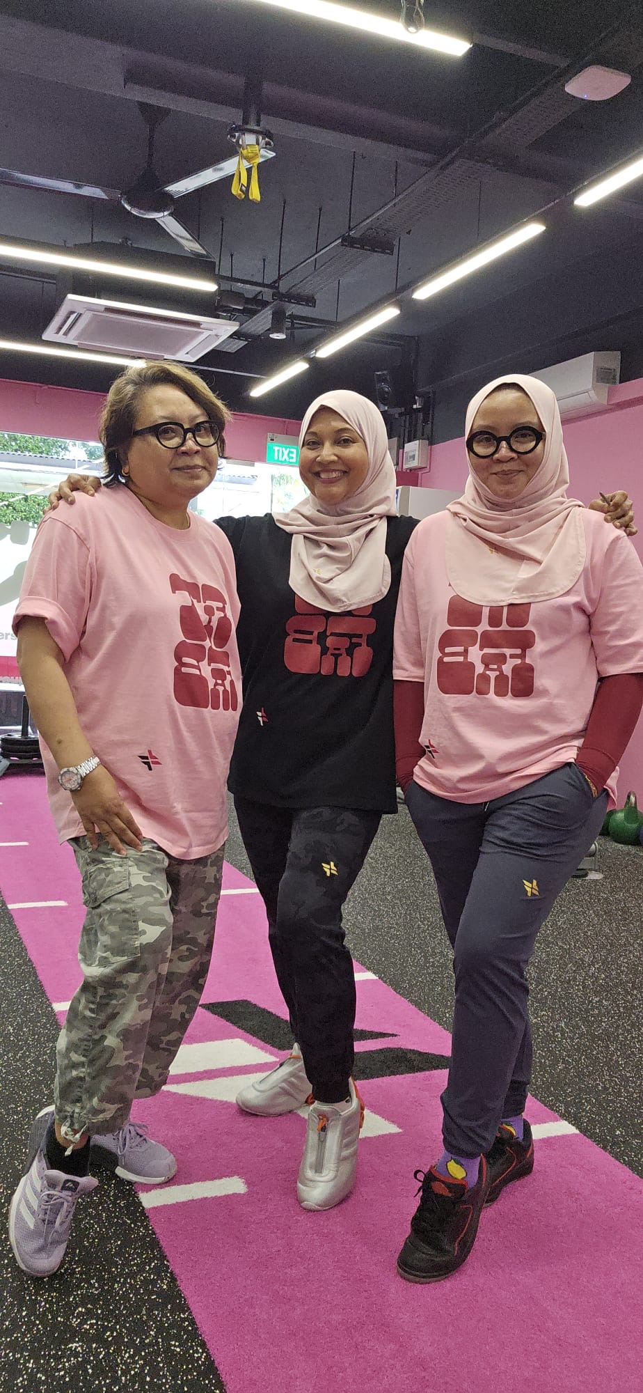 Three FitFab.sg members in matching pink and black tees