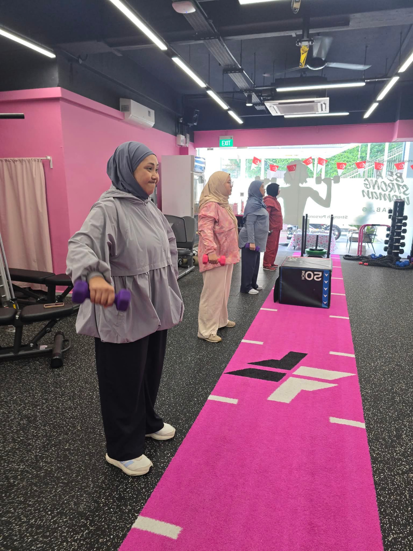 Women performing controlled dumbbell raises at FitFab.sg