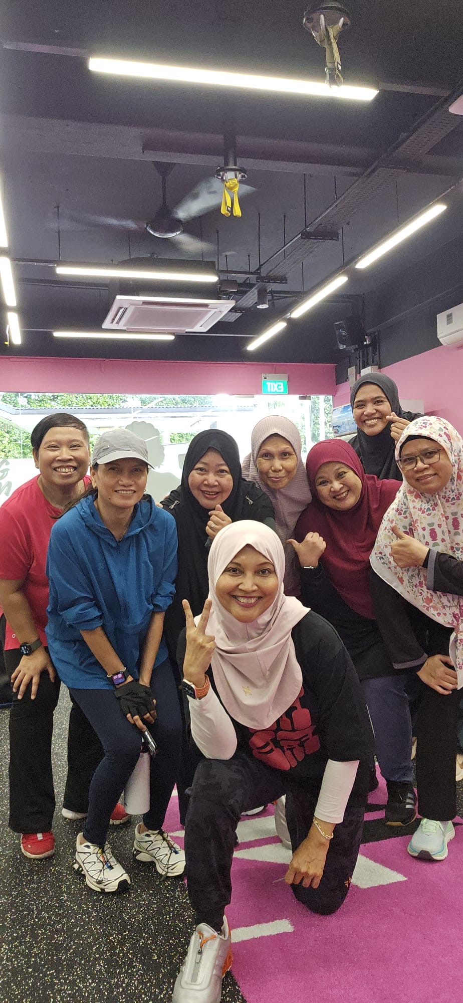 A large group of FitFab.sg members posing together at the pink gym