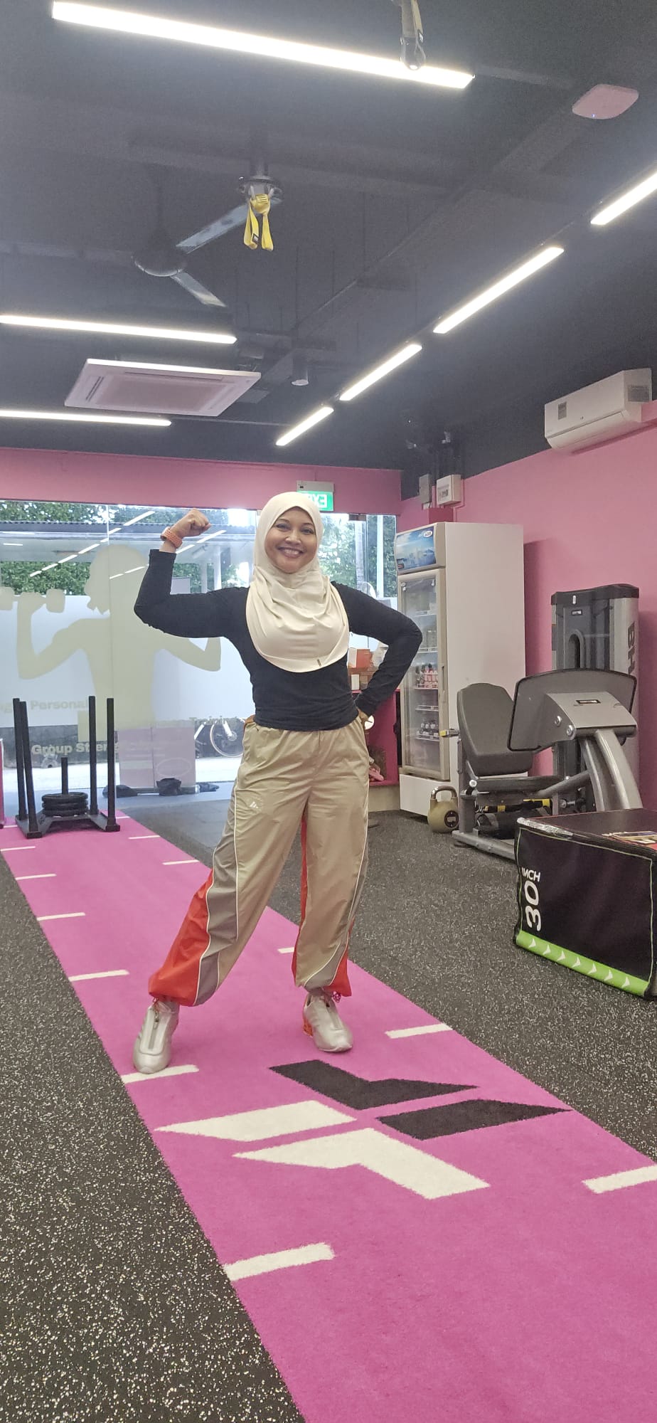 Haslinda Ali striking a strong bicep pose at the FitFab.sg pink gym